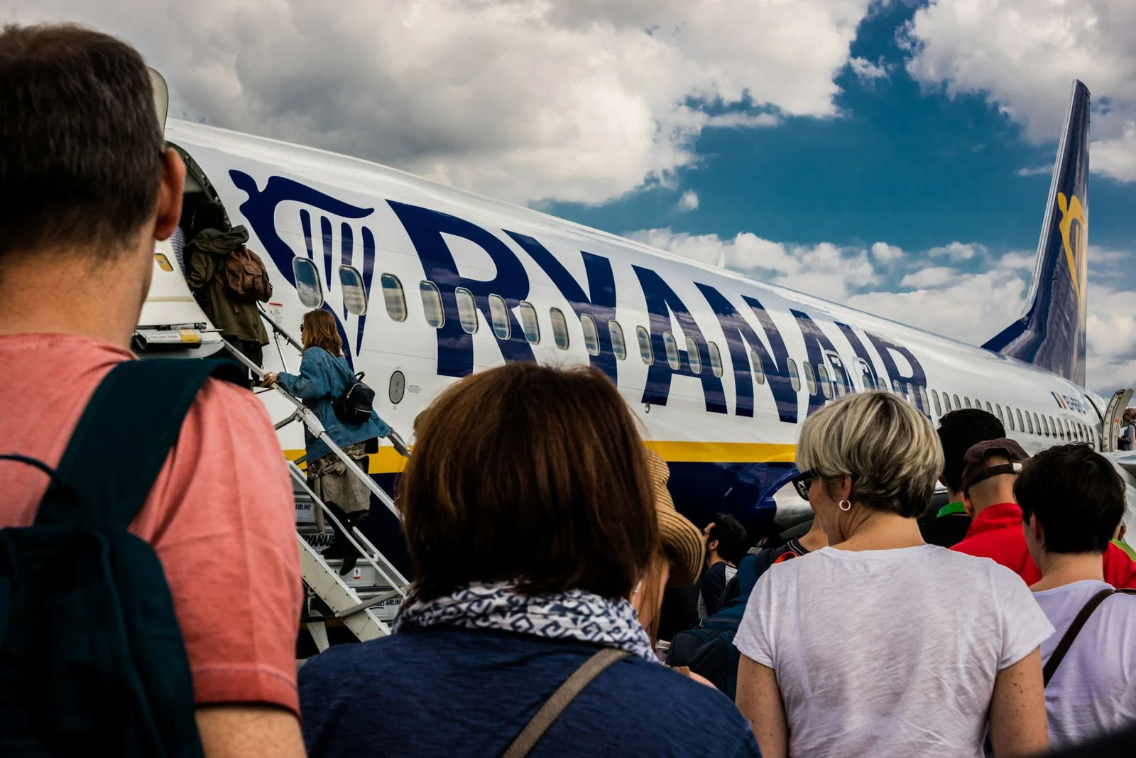 Travellers carrying bags in the boarding queue for a Ryanair aircraft