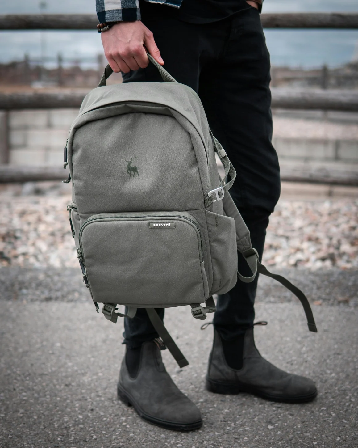 Zaino da viaggio grigio tenuto per la maniglia, con tasche visibili